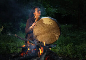Shamanic woman conducts ritual A woman is drumming on the fire